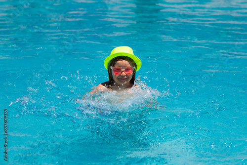 Child splashing in swimming pool. Swim water sport activity on summer vacation with child. © Volodymyr