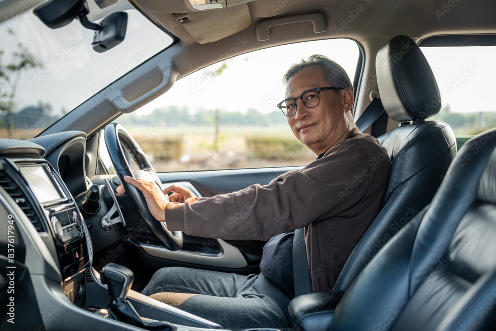 Senior Asian man drives a car vehicle on a clear day. With beautiful blue sky. He smiling driving to travel by car. Old man getting new car. Senior Asian man drives a car vehicle on a clear day. With beautiful blue sky. He smiling driving to travel by car. Old man getting new car.