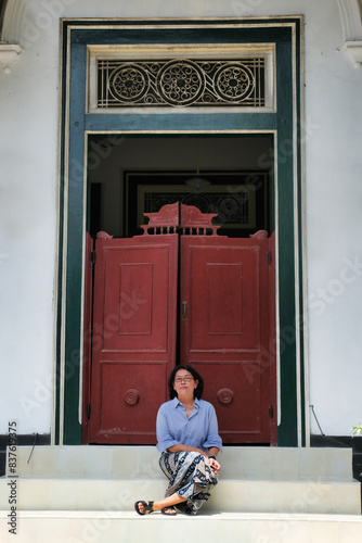 A woman sitting on a door step of an old vintage Javanese house in Yogyakarta photo