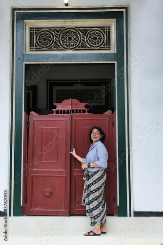 Woman standing in the front door of an old vintage Javanese architectural house photo