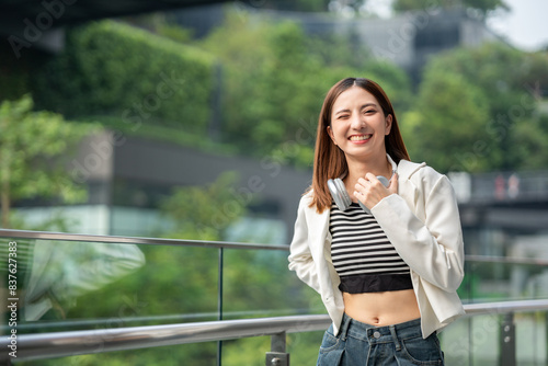 Young asian woman fashion lifestyle with headphone standing posing in urban city downtown. Happy attractive charming asian female living in city. People and lifestyle.