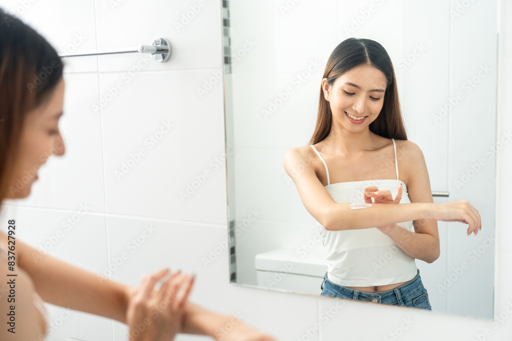 Beautiful smiling happy young asian woman with beauty skin care treatment lotion on the body. Charming female lady looking mirror applying body cream Facial treatment beauty and spa Beautiful smiling happy young asian woman with beauty skin care treatment lotion on the body. Charming female lady looking mirror applying body cream Facial treatment beauty and spa