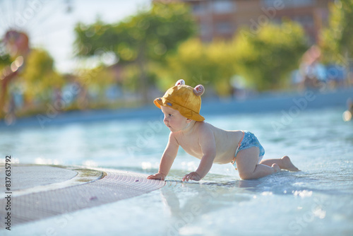 a little half a year old, a baby baby crawling on the water, smiling, outdoors, in a panama hat, in diapers, in the sun at the resort. photo