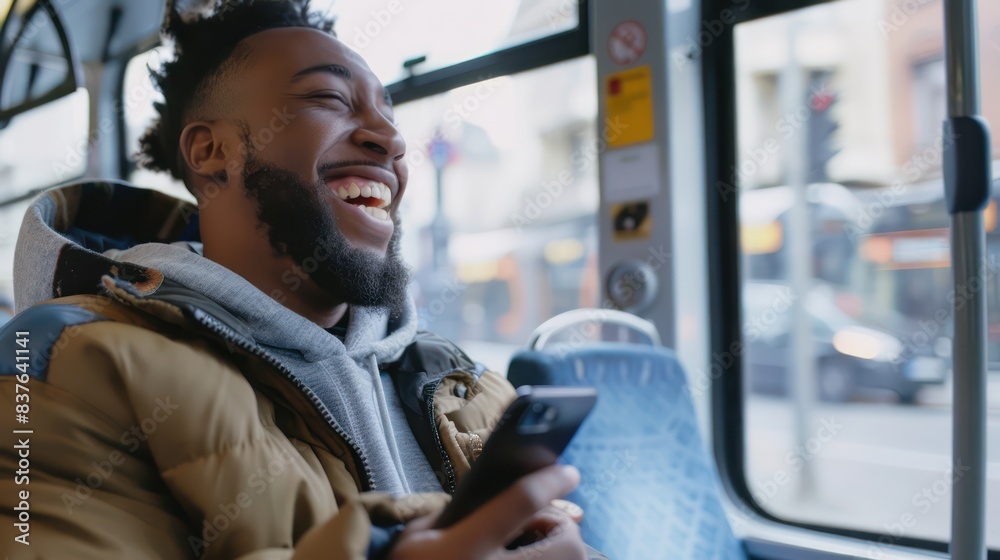 A candid photo of a handsome young man laughing at something on his smartphone screen while on the bus. A candid photo of a handsome young man laughing at something on his smartphone screen while on the bus.