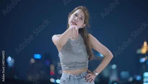 Shot of young beautiful asian woman shouting and yelling at camera showing human emotion gesture, frustrated woman, woman in bad mood unhappy, not pleased unsatisfied, night shot with nice city view 