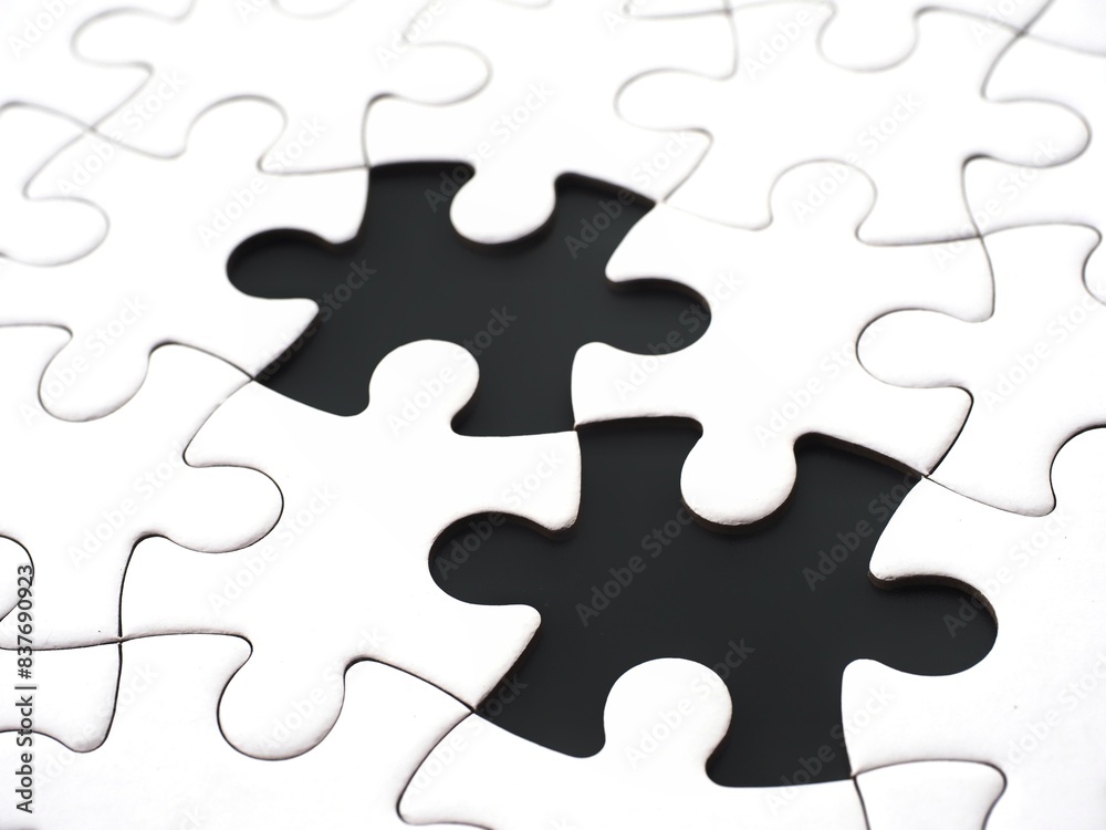 A close-up of an incomplete jigsaw puzzle with two missing pieces on a black background, symbolizing incompleteness, imperfection, mistery or loss A close-up of an incomplete jigsaw puzzle with two missing pieces on a black background, symbolizing incompleteness, imperfection, mistery or loss