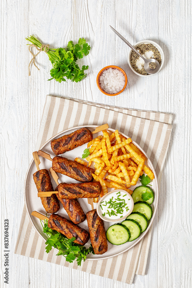 minced beef skewers with potato fries on plate minced beef skewers with potato fries on plate