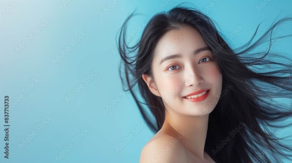 Asian woman with long black hair smiling against blue background. Asian woman with long black hair smiling against blue background.