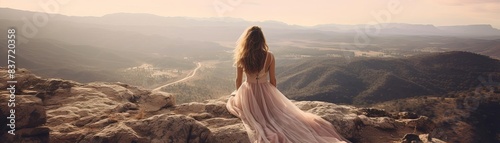 A girl in a flowing dress sitting on a rocky mountain ledge, with a panoramic view of the valleys below, Realistic, Soft Colors, Photography, Breathtaking