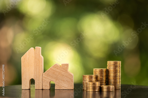 Home model and stack gold coin with growing the interest in the public park, Savings money for buy house and loan to business investment for real estate concept.
