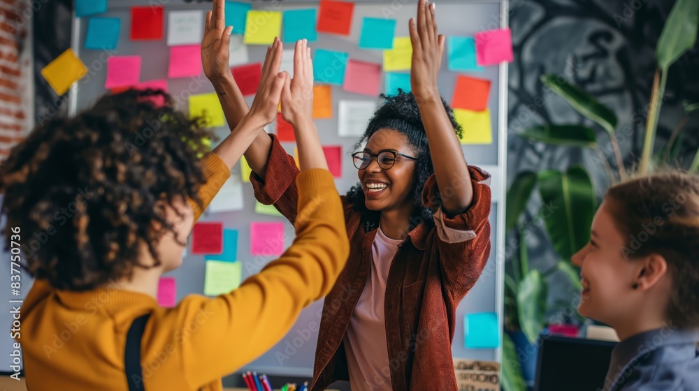 Two energetic colleagues celebrate a success with a high-five amid a colorful background of sticky notes