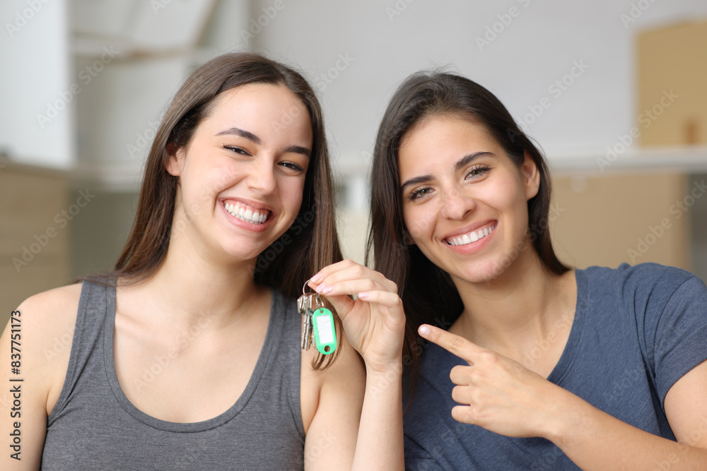 Two happy roommates showing keys moving house Two happy roommates showing keys moving house