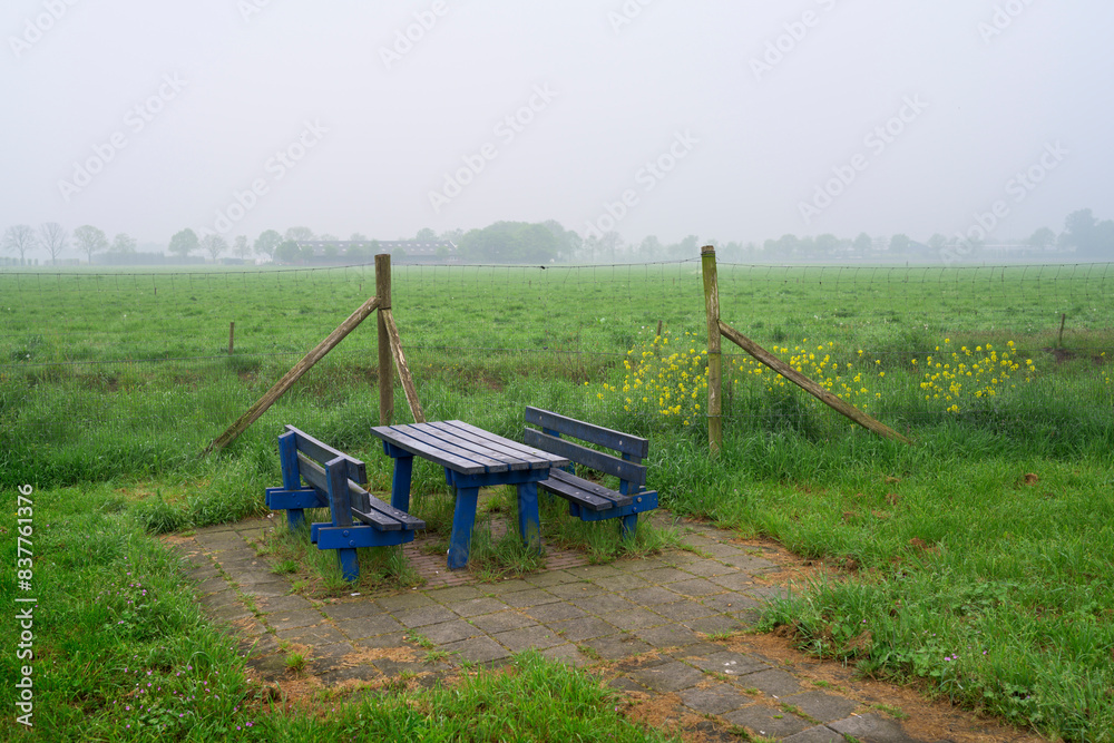 Empty benches in front of green field during foggy weather Empty benches in front of green field during foggy weather