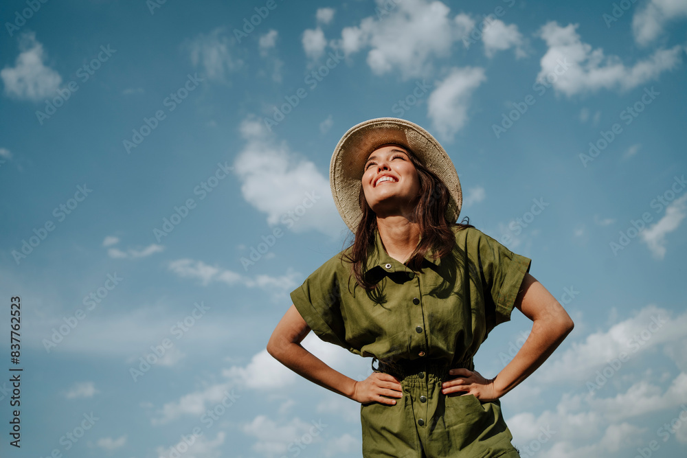 Happy young woman wearing green jumpsuit and hat under sky Happy young woman wearing green jumpsuit and hat under sky