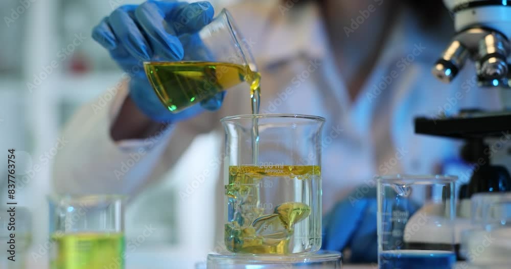 Pouring and mixing yellow liquid and with water or solvent in a chemistry laboratory