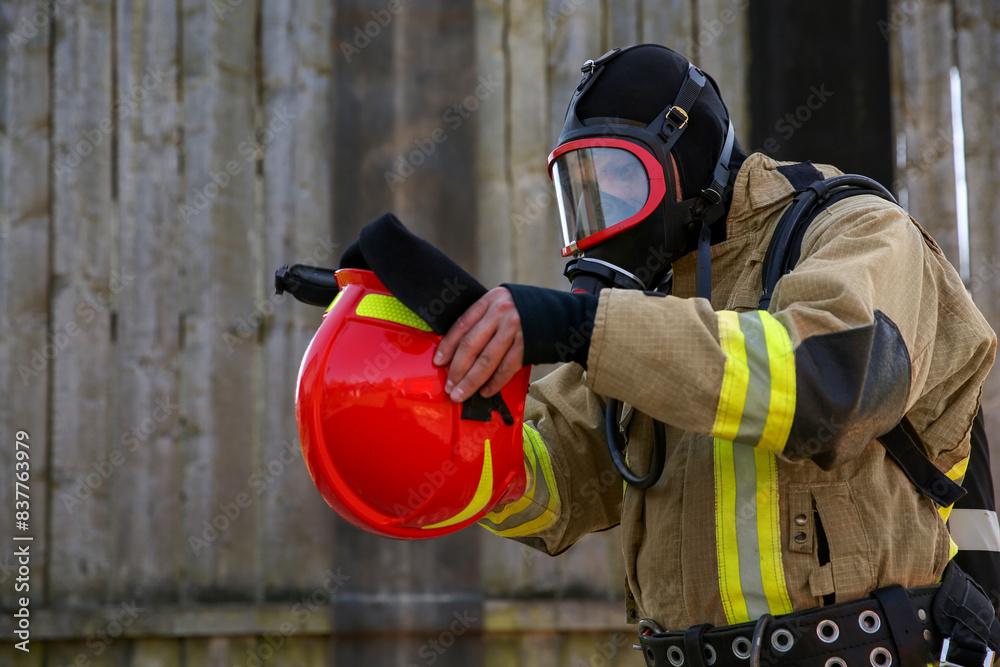 Fototapeta premium Firefighter in uniform wearing helmet and mask outdoors