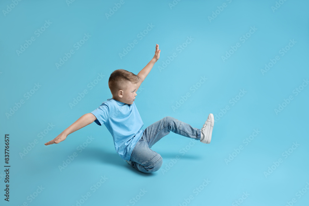 Happy little boy dancing on light blue background Happy little boy dancing on light blue background