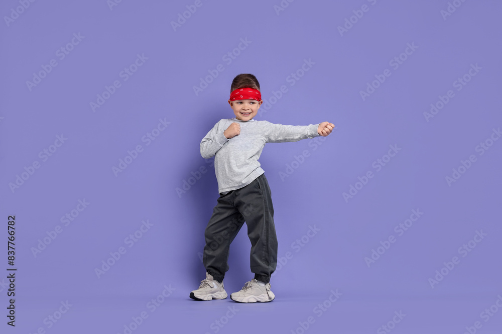 Happy little boy dancing on violet background Happy little boy dancing on violet background