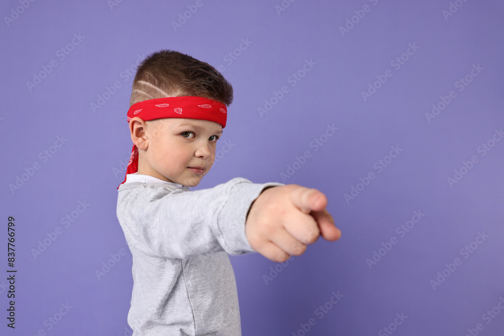 Happy little boy pointing at something on violet background. Space for text Happy little boy pointing at something on violet background. Space for text