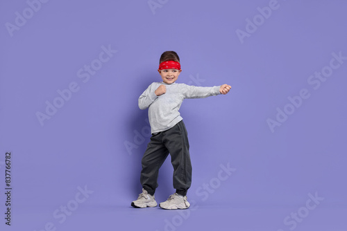 Happy little boy dancing on violet background