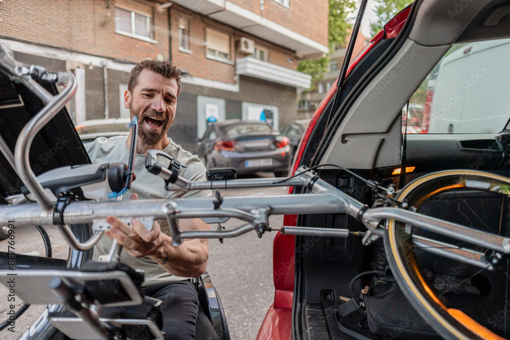 Happy disabled man loading handcycle in car trunk Happy disabled man loading handcycle in car trunk