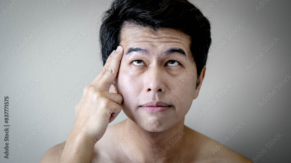 Portrait of Asian man touching his face showing forehead creases wrinkle. Facial complexion treatment and rejuvenation by skincare and cosmetic cream. Mens beauty cosmetology. Anti aging concept Portrait of Asian man touching his face showing forehead creases wrinkle. Facial complexion treatment and rejuvenation by skincare and cosmetic cream. Mens beauty cosmetology. Anti aging concept