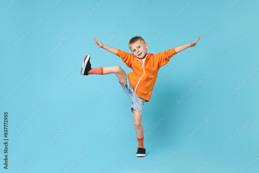 Happy little boy dancing on light blue background Happy little boy dancing on light blue background