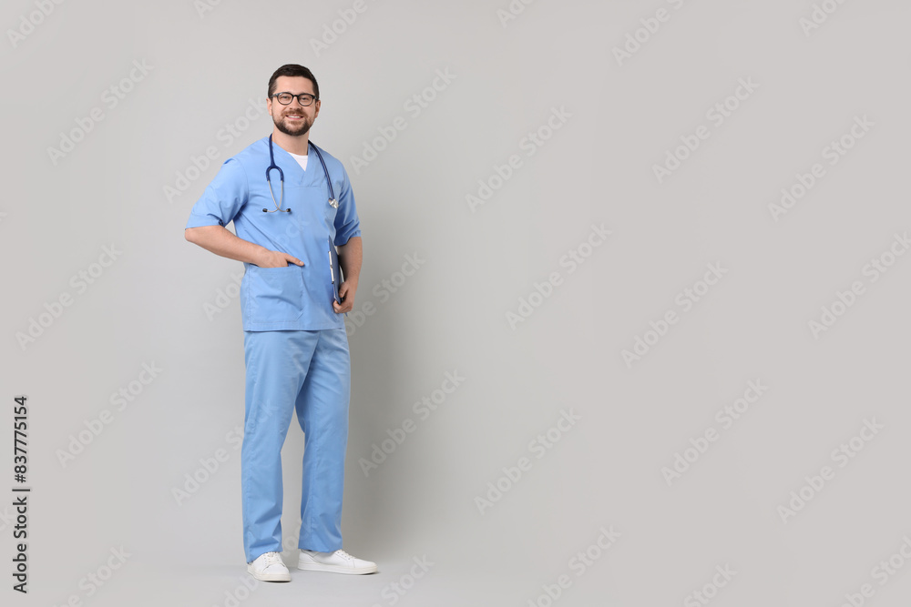 Full length portrait of smiling doctor on light grey background. Space for text Full length portrait of smiling doctor on light grey background. Space for text