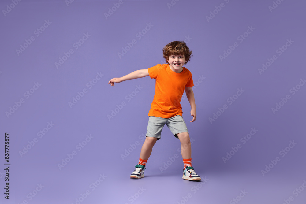 Happy little boy dancing on violet background Happy little boy dancing on violet background