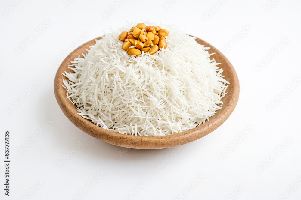White shredded coconut with brown nuts in wooden bowl White shredded coconut with brown nuts in wooden bowl