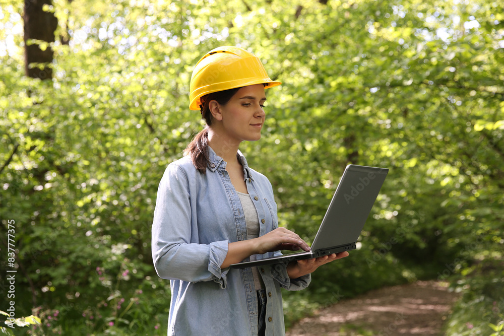Forester in hard hat with laptop working in forest Forester in hard hat with laptop working in forest