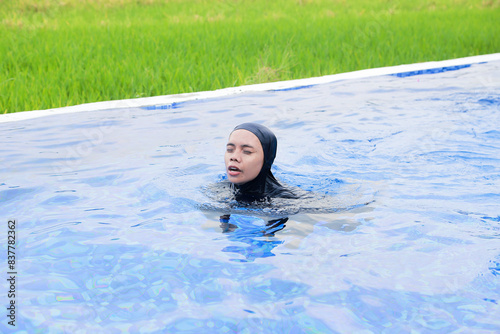 Portrait of a happy young Asia woman relaxing in the infinity edge pool at resort