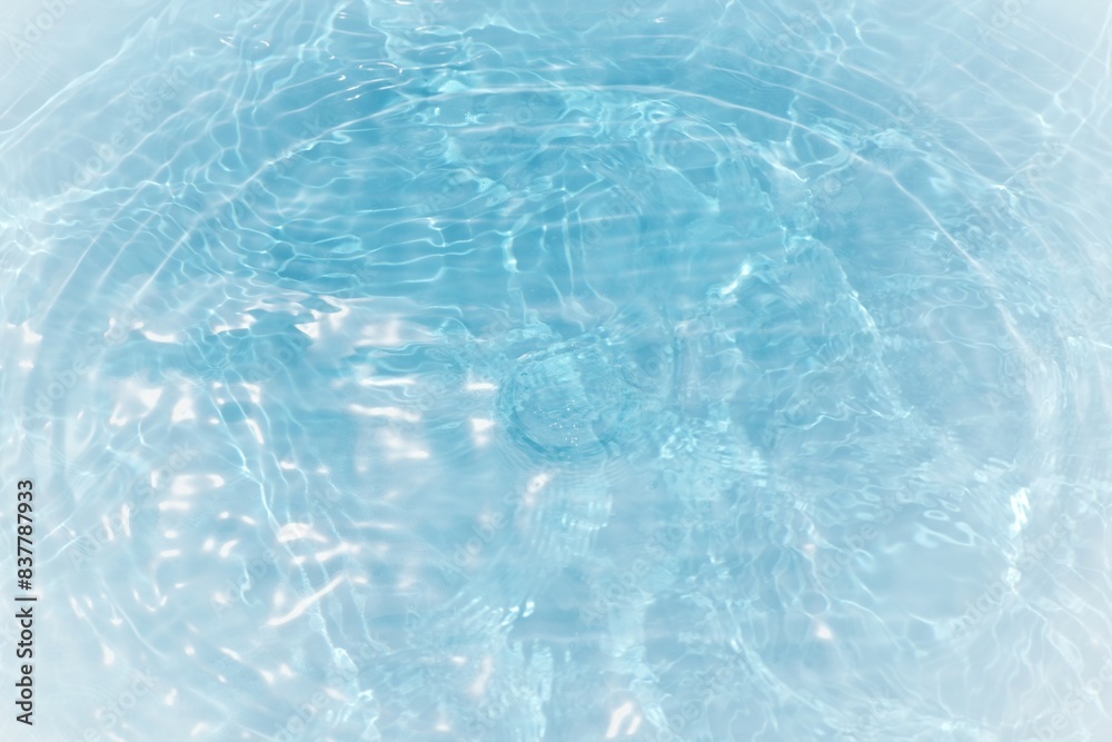 Obraz premium Blue water with ripples on the surface. Defocus blurred transparent blue colored clear calm water surface texture with splashes and bubbles. Water waves with shining pattern texture background. 