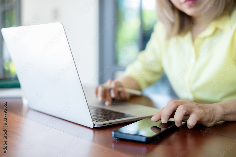 Fototapeta premium Business woman sitting in office at table and using smartphone