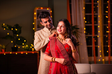 Indian husband presenting gold necklace to wife on diwali festival celebration