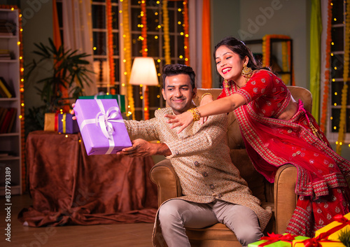 Playful Indian young couple celebrating diwali with gifts, wife trying to get hold of present from husband © StockImageFactory