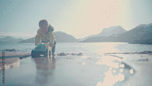 Boy plays with toy dump truck on a beautiful beach in Northern Norway right outside of Tromso, Norway. With big mountains in the background, this is a stunning capture. #untraceableglobal photo