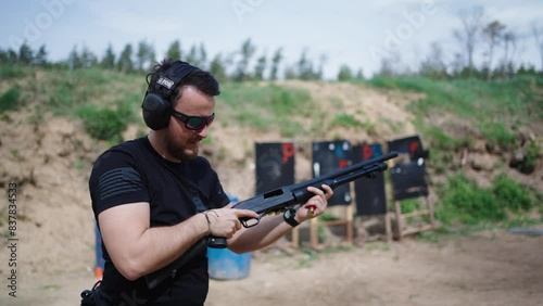 Muscular caucasian male hold and reload shotgun at Olesko shooting range photo