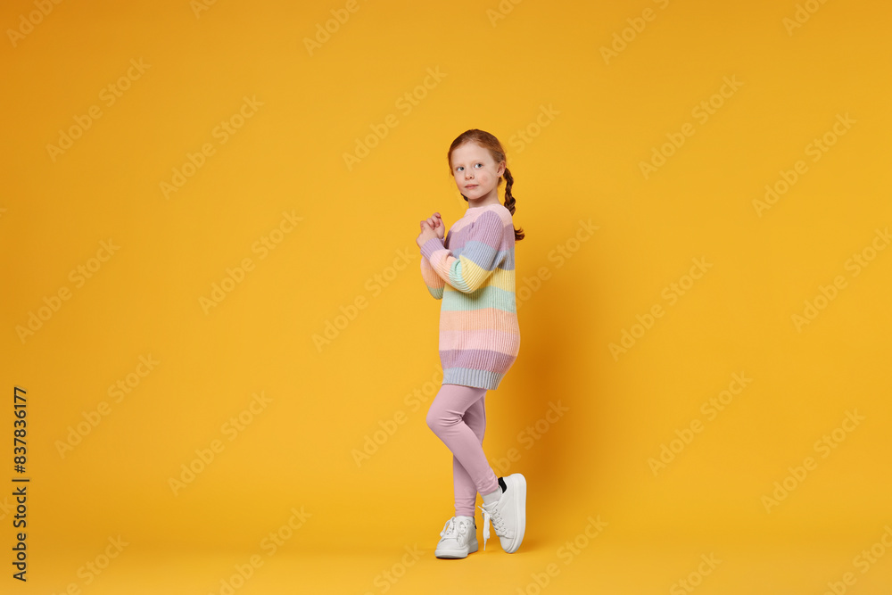 Cute little girl dancing on orange background Cute little girl dancing on orange background