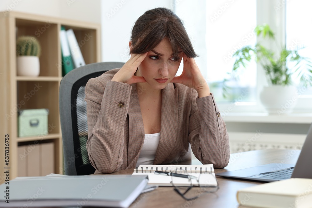 Overwhelmed office worker sitting at table with laptop indoors Overwhelmed office worker sitting at table with laptop indoors