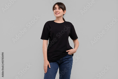 Smiling woman in stylish black t-shirt on light grey background