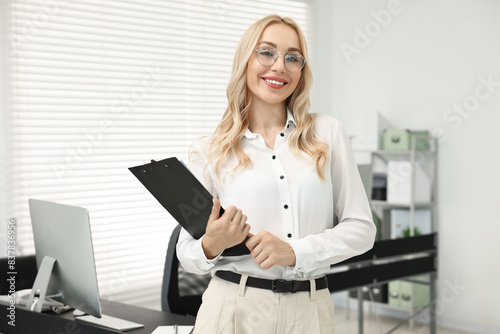Happy secretary with glasses and clipboard in office © New Africa