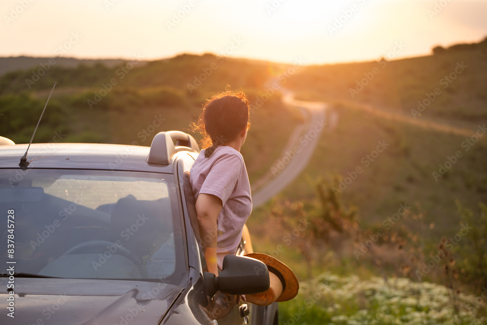 Fototapeta premium Girl with hat in the window of the car. Adventure, vacation, road trip concept.