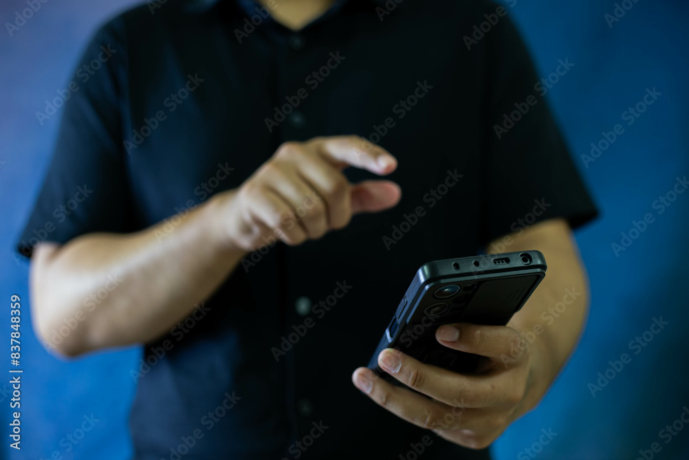 Fototapeta premium A man stands holding an iPad, using his finger to point at the screen, showcasing modern technology.