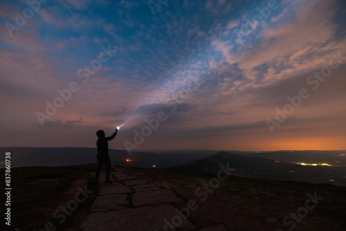 Fotografie Silhouette of a woman with torch under night sky with stars and clouds