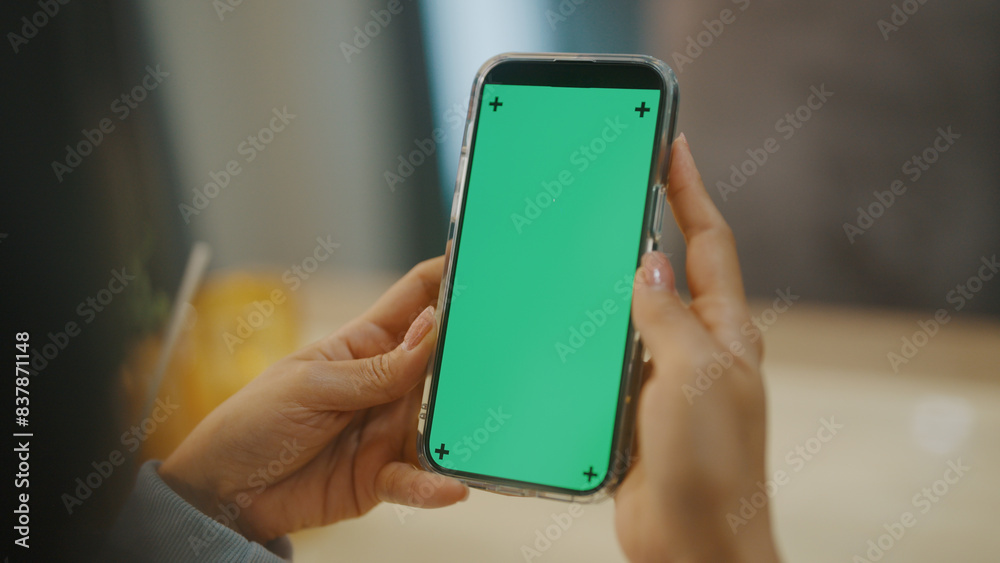 A woman uses a mobile phone or tablet with a green screen to watch videos, surf social media, or have an online conference. A woman uses a mobile phone or tablet with a green screen to watch videos, surf social media, or have an online conference.