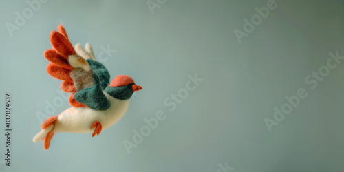 Needle felted colorful toy bird flying. Felt dove on a blue background with copy space. photo