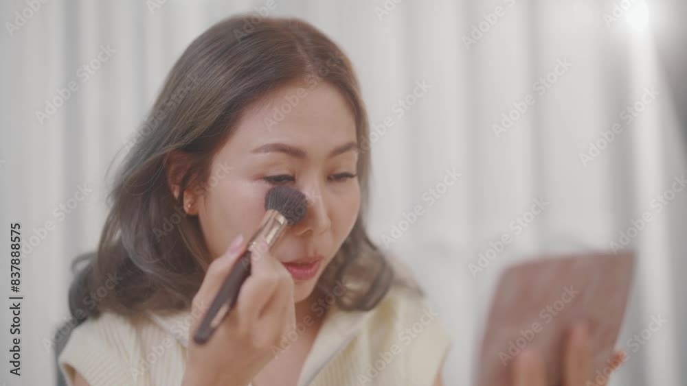 A woman puts on makeup and blush to boost her confidence before leaving the house.