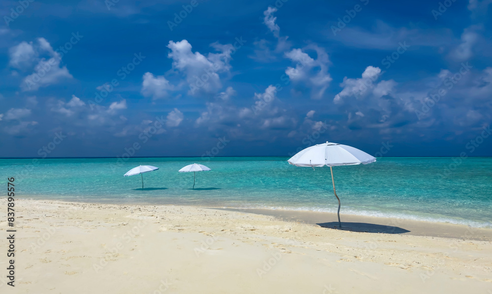 Summer tropical with white umbrella on the beach with  blue sky background