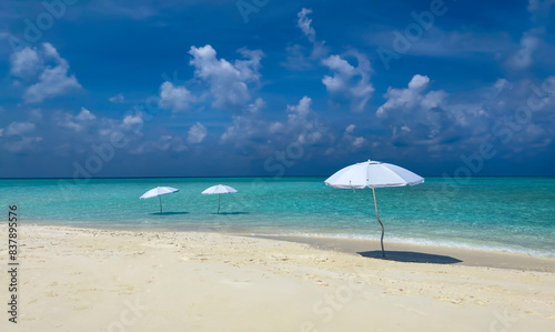 Fototapeta Naklejka Na Ścianę i Meble -  Summer tropical with white umbrella on the beach with  blue sky background